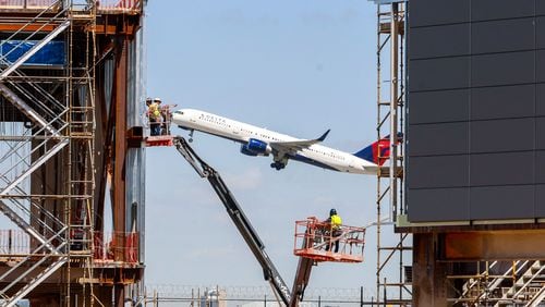Construction workers are seen installing panels in the exterior of Modules 3 and 4 as a Delta airplane flies by on Wednesday, March 27, 2024. The prefabricated structures are among those that will be transported hydraulically and connected to Concourse D at Hartsfield-Jackson Atlanta Airport.
Miguel Martinez /miguel.martinezjimenez@ajc.com