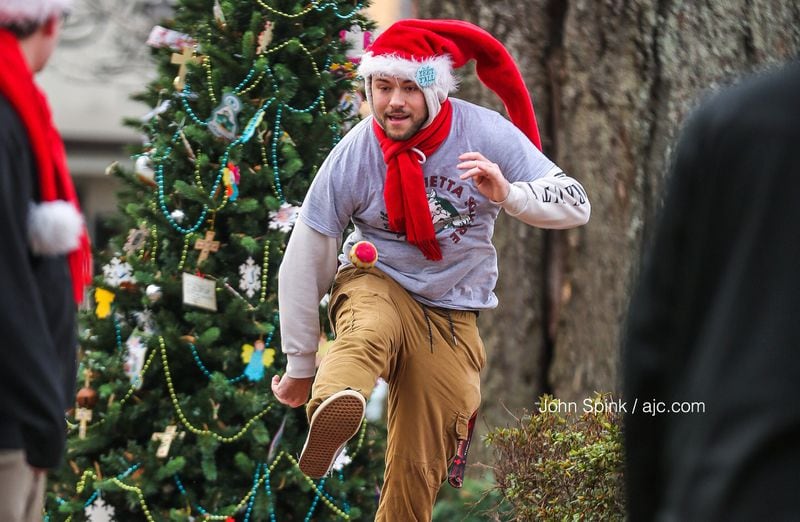 Ben Snowden, 19, one of Santa's helpers, keeps warm by playing hacky sack at Santa on the Square in Marietta on Wednesday morning. JOHN SPINK / JSPINK@AJC.COM