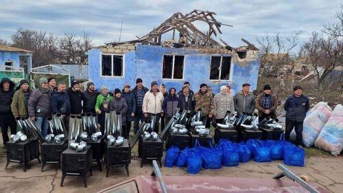 Ken Ward and volunteers stand in front of a damaged home in Ukraine, before handing out blankets and installing wood-fired stoves, which can be used for both heating and cooking. (Photo Courtesy of HelpingUkraine.U.S.)