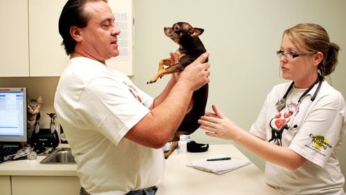 Dr. Anthony Krawitz, left, and Autumm Mitchell check Rexx for masses under his skin during a reduced-fee clinic at Calusa Veterinary Center in this Palm Beach Post file image.