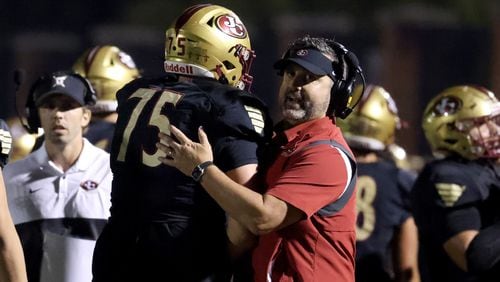 Former Johns Creek head coach Matt Helmerich, now at Peachtree Ridge, celebrates a touchdown with offensive lineman Tyler Gibson (75) during the second half of a 2021 game against Riverwood. Johns Creek won the game 40-32.