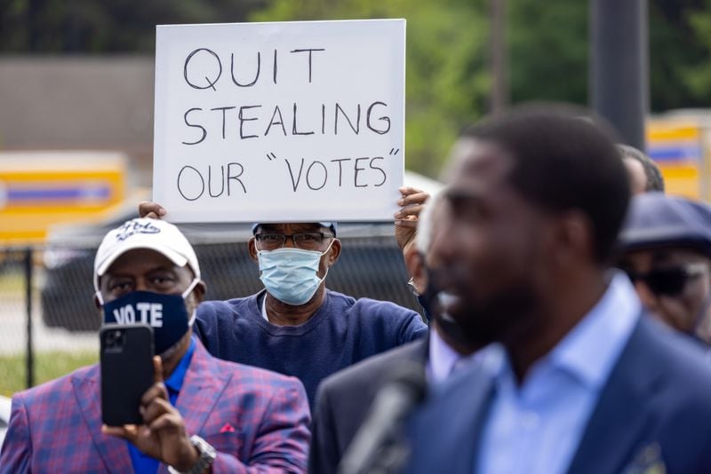 A man holds a sign saying "Quit Stealing Our 'Votes'" as African American religious leaders announce a boycott of Home Depot over inaction on recent voting legislation in Georgia, across from a Home Depot in Decatur on April 20, 2021. (Courtesy of Nathan Posner)
