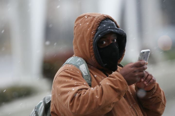 A person takes a photo with his phone on Peachtree Road looking over I-85, while the snow is starting to fall in metro Atlanta on Sunday, Jan. 16th, 2022. Miguel Martinez for The Atlanta Journal-Constitution