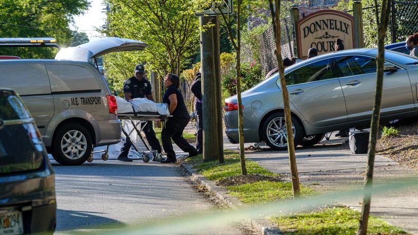 The body of a man who was found shot and dead inside a sedan is lifted into a van. The sedan crashed into a fence at a southwest Atlanta apartment complex on Friday, April 15, 2022. The crash occurred outside of the Donnelly Courts apartments.  (Arvin Temkar / arvin.temkar@ajc.com)