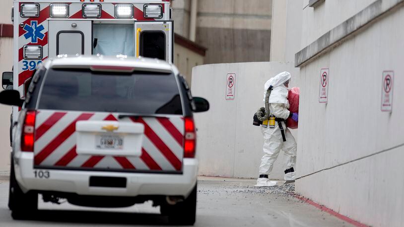 A person wearing a haz-mat suit carries a wrapped object out of an ambulance into Emory University Hospital after an ebola patient was taken in for treatment, Tuesday, Sept. 9, 2014, in Atlanta. The fourth American aid worker sickened with the Ebola virus arrived Tuesday morning for treatment at Emory University Hospital, where two others have been successfully treated. (AP Photo/David Goldman)