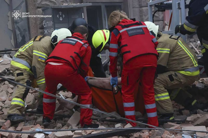 In this photo provided by the Ukrainian Emergency Service, rescuers and ambulance workers carry a person on the scene of a Russian attack in Dnipro, Ukraine, Friday, April 19, 2024. (Ukrainian Emergency Service via AP Photo)