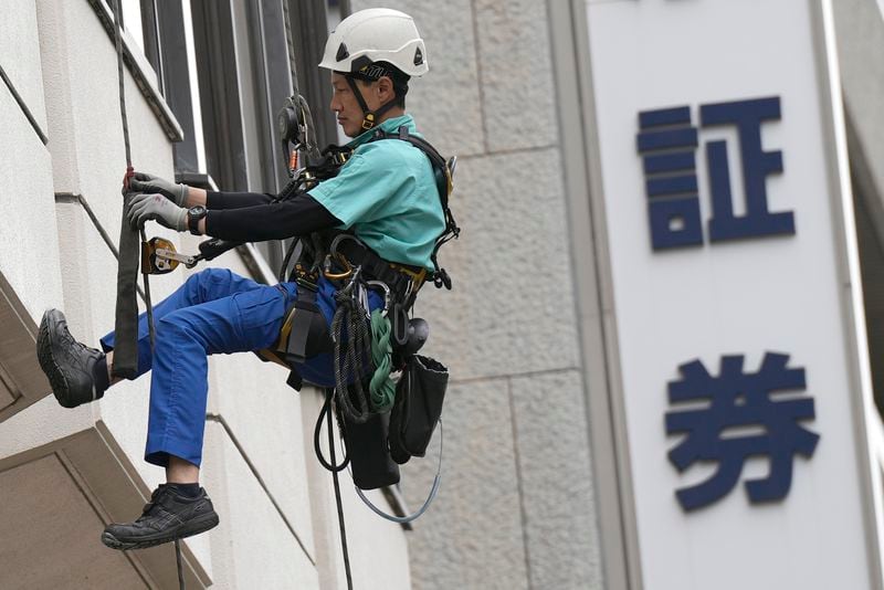 A window cleaner works along the window of at a securities firm building Tuesday, April 30, 2024, in Tokyo. Japanese characters read as "securities." (AP Photo/Eugene Hoshiko)