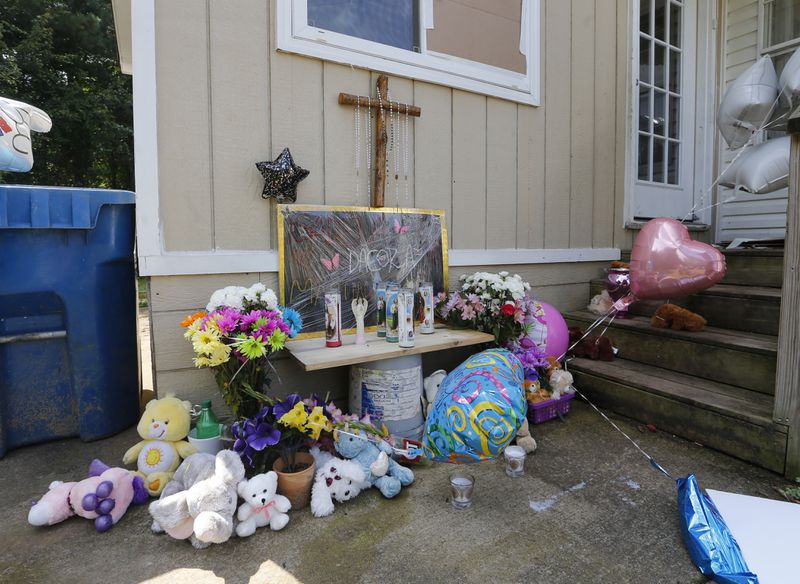 Flowers and stuffed toys left on the doorstep of a home where four children and their father were stabbed to death are shown Friday, July 7, 2017, in Loganville , Ga. Isabel Martinez the children's mother and the man's wife has been charged with the crimes. (AP Photo/John Bazemore)