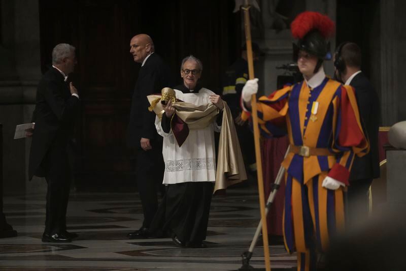 A deacon brings the papal robe for Pope Francis who will preside over the second vespers in St. Peter's Basilica on Ascension Day, Thursday, May 9, 2024, after reading the papal bull 'Spes non confundit' (Latin for, hope does not disappoint), the official decree establishing the Catholic Holy Year: a once-every-quarter-century event that is expected to bring some 32 million pilgrims to Rome (AP Photo/Gregorio Borgia)