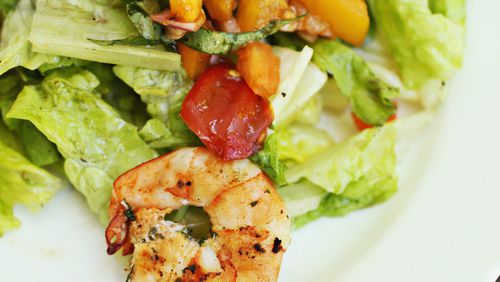 In this beautiful presentation salad, shrimp is marinated for an hour and then grilled and served on top of a bed of mixed greens with Heirloom tomatoes. (Juli Leonard/Raleigh News & Observer/TNS)