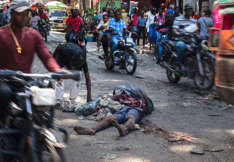 A body lies in the middle of the street as commuters make their way through the Petion-Ville neighborhood of Port-au-Prince, Haiti, Monday, April 22, 2024. (AP Photo/Ramon Espinosa)