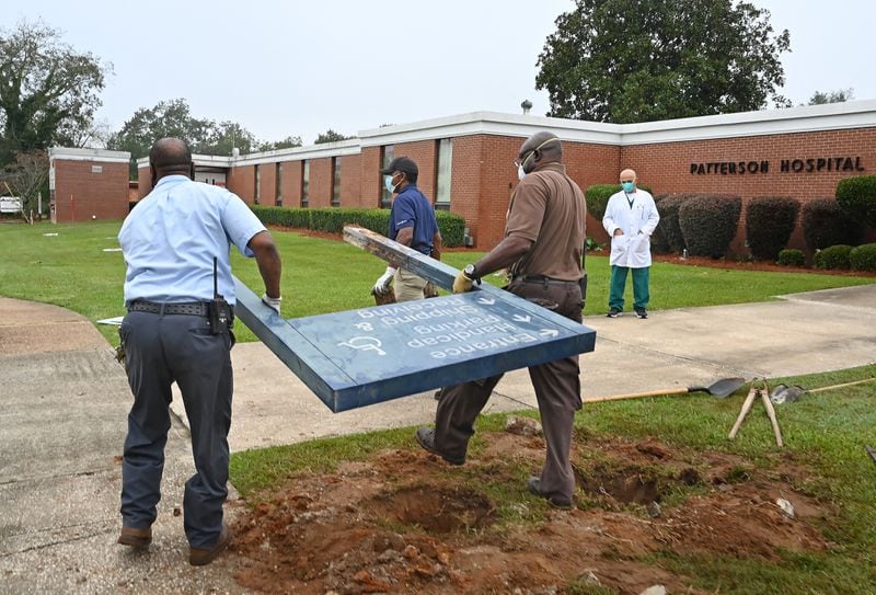 Dr. Abdollatif Saleh Ghiathi (right) watches as maintenance staff remove a sign outside the Southwest Georgia Regional Medical Center as the hospital closes Oct. 2, 2020.