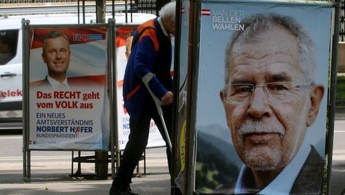 A man walks between election posters of Alexander Van der Bellen, candidate for presidential elections and former head of the Austrian Greens, front, and Norbert Hofer, candidate for presidential elections of Austria's right-wing Freedom Party, FPOE, in Vienna, Austria, Thursday, May 19, 2016. (AP Photo/Ronald Zak)