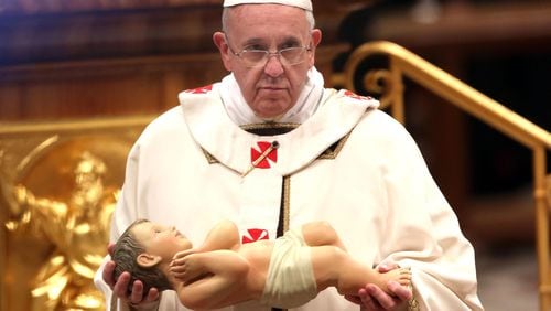 Pope Francis holds the crib effigy of the infant Jesus. A topless protester tried to steal the doll on Christmas Day in St. Peter's Square.