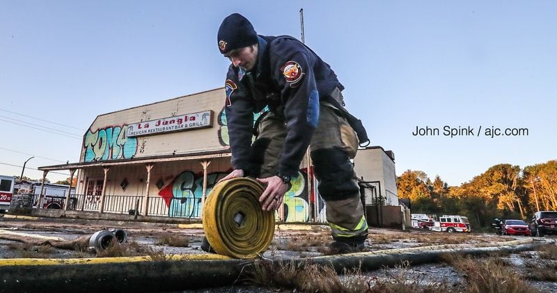 An Atlanta firefighter rolls up a hose line after putting out a fire in a shed behind an abandoned Mexican restaurant.