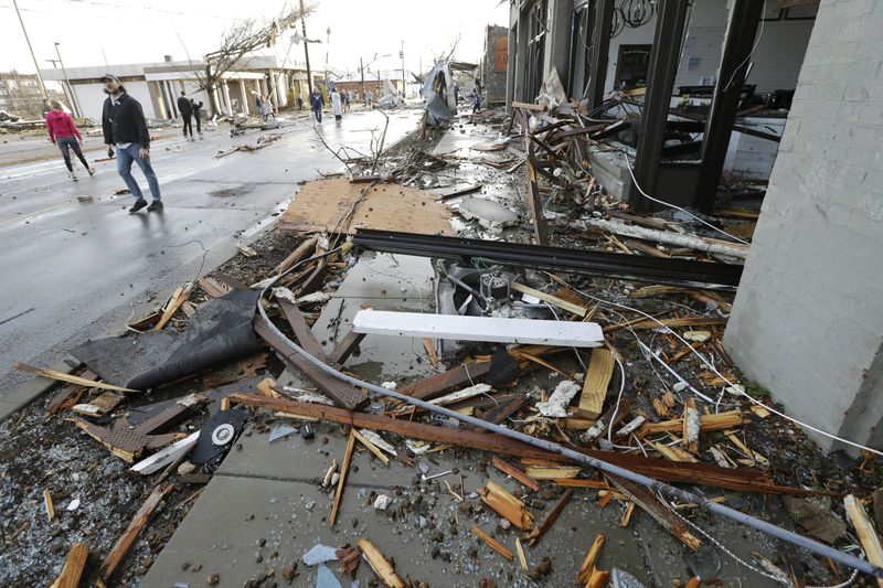 People pass by businesses destroyed by storms Tuesday, March 3, 2020, in Nashville, Tenn. Tornadoes ripped across Tennessee early Tuesday, shredding buildings and killing multiple people.  (AP Photo/Mark Humphrey)