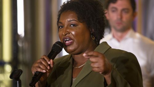 Stacey Abrams speaks during the "One Georgia" rally in Marietta on Nov. 1, 2022, while U.S. Sen. Jon Ossoff looks on. (Christina Matacotta for the AJC)