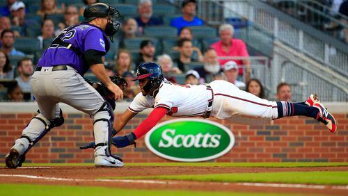 Braves' Ronald Acuna dives into home before the tag by Rockies catcher Chris Iannetta to score a run during the first inning Friday, Aug. 17, 2018, at SunTrust Park in Atlanta.