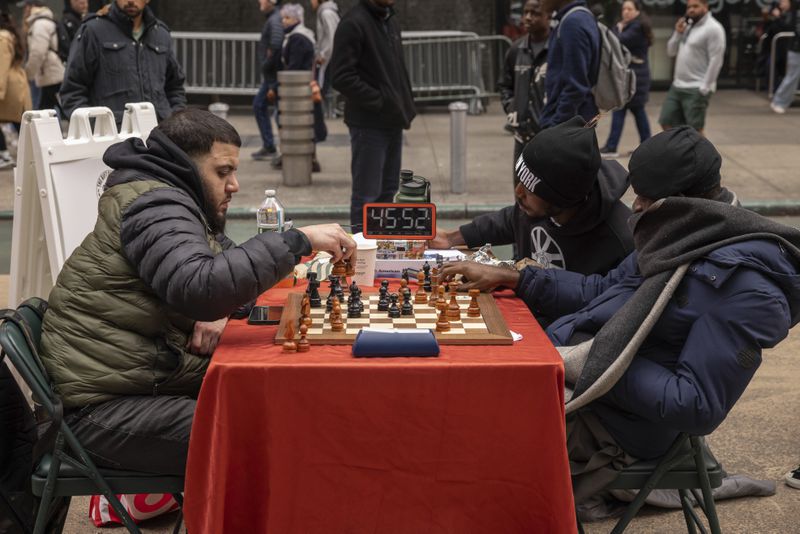 Tunde Onakoya, right, a Nigerian chess champion and child education advocate, plays a chess game in Times Square, Friday, April 19, 2024, in New York. (AP Photo/Yuki Iwamura)