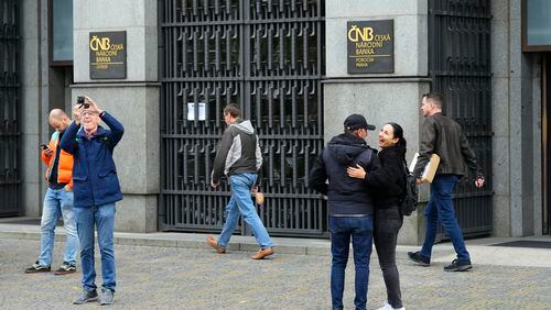 FILE - People stand outside the Czech central bank in Prague, Czech Republic, on Nov. 2, 2023. On Thursday May 2, 2024, the Czech Republic's central bank cut its key interest rate for the fourth straight time amid falling inflation and signs of the economy's recovery. The cut by a half-percentage point brought the interest rate down to 5.25%. (AP Photo/Petr David Josek, File)