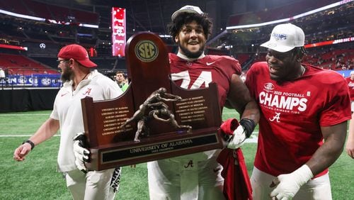 Alabama Crimson Tide players including offensive lineman Kadyn Proctor (74) celebrate after defeating the Georgia Bulldogs 27-24 in the SEC Championship football game at the Mercedes-Benz Stadium in Atlanta, on Saturday, December 2, 2023. (Jason Getz / Jason.Getz@ajc.com)
