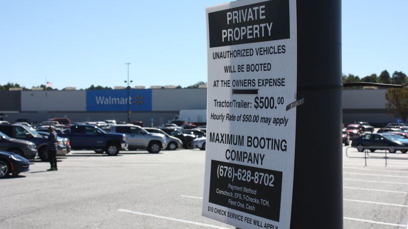 Signs in the Newnan Crossing shopping center in Newnan, Ga., warn owners of “unauthorized vehicles” they are subject to booting.