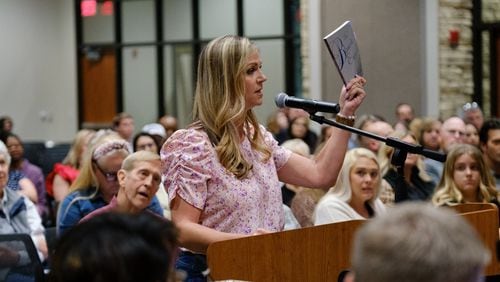 Chelle Brown holds Toni Morrison’s "The Bluest Eye" while speaking at a Cherokee County school board meeting in Canton on Thursday, April 21, 2022. Brown and some other parents advocate for removing books they deem objectionable from Cherokee County schools. (Arvin Temkar / arvin.temkar@ajc.com)