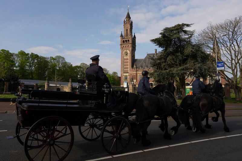 A horse-drawn cart passes in front of the International Court of Justice in The Hague, Netherlands, Tuesday, April 30, 2024, where Mexico is taking Ecuador to the United Nations' top court accusing the nation of violating international law by storming into the Mexican embassy in Quito and arresting former Ecuador Vice President Jorge Glas, who had been holed up there seeking asylum in Mexico. (AP Photo/Peter Dejong)