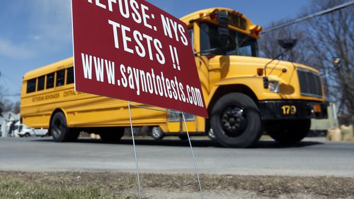A school bus passes a sign encouraging parents to  opt their children out of end-of-the-year state tests in New York.  Georgia is about to launch a pilot program that would allow districts to create alternatives to its state exams, the Milestones.