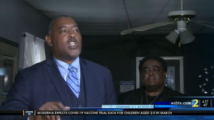 Attorney Dexter Wimbish talks to reporters Thursday in Griffin after his client, Curtis Keith Bankston (background), was arrested and charged with false imprisonment. (Credit: Channel 2 Action News)