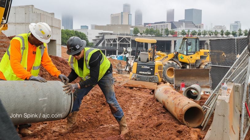 Fog covers Atlanta as Reeves and Young Construction workers Joseph Jackson, left, and Tom Palmer put piping into place at the Home Depot Backyard next to Mercedes Benz Stadium.