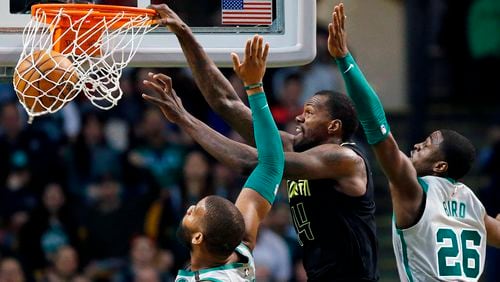 Atlanta Hawks' Dewayne Dedmon (14) dunks against Boston Celtics' Greg Monroe, left, and Jabari Bird (26) during the fourth quarter Sunday, April 8, 2018, in Boston.