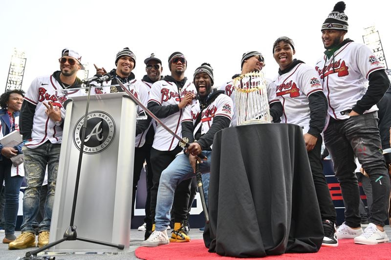 Braves players pose in front of the championship trophy. (Hyosub Shin / Hyosub.Shin@ajc.com)