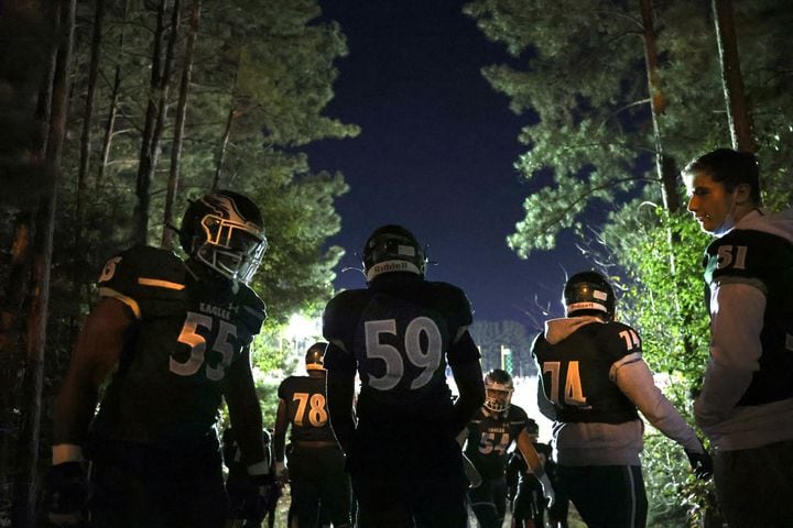 Collins Hill players T'Kaveon Lanier (55), Giles-Evans Mboumi (59), Bentley White (74) and others wait in the woods before they walk to their football stadium before their game against North Gwinnett. JASON GETZ FOR THE ATLANTA JOURNAL-CONSTITUTION