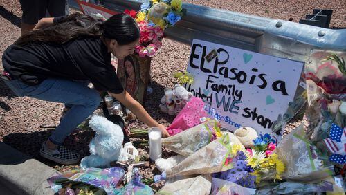 A woman places flowers on Sunday, August 4, 2019, beside a makeshift memorial outside the Cielo Vista Mall Wal-Mart (background), where a shooting left 20 people dead in El Paso, Texas. (Mark Ralston/AFP/Getty Images/TNS)