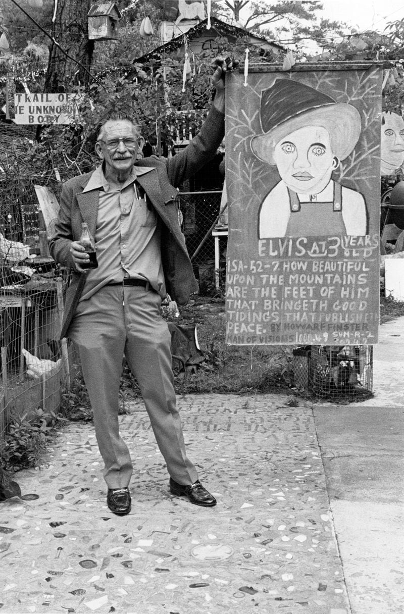 Howard Finster with baby Elvis banner, 1981 at Paradise Garden. Photo by Tom Patterson