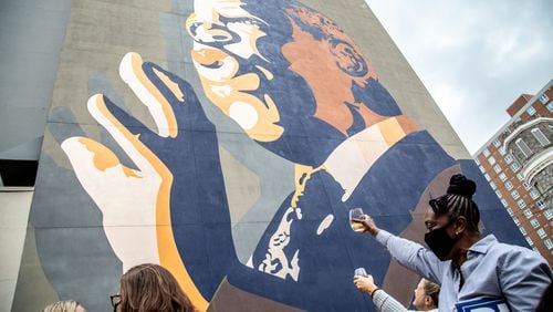 People raise a glass of champagne to the John Lewis mural after the election was called for Joe Biden Saturday, November 7, 2020.   STEVE SCHAEFER / SPECIAL TO THE AJC 