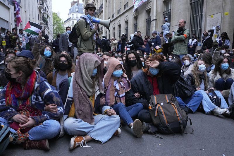 Students stage a sit in outside Sciences-Po university in Paris Friday, April 26, 2024. Students in Paris inspired by Gaza solidarity encampments at campuses in the United States blocked access to a campus building at a prestigious French university Friday, prompting administrators to move all classes online. The pro-Palestinian protest at the Paris Institute of Political Studies, known as Sciences Po, came two days after police broke up a separate demonstration at one of the university's amphitheaters. (AP Photo/Michel Euler)