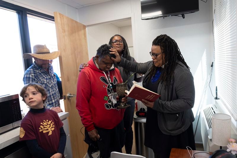 The Rev. Kim Jackson, right, and Shereetha Jackson behind, both with Church of the Common Ground, lay hands on Roy Dunn while blessing him and his home at The Melody, a 40-unit transitional housing development in Atlanta on Wednesday, Feb. 14, 2024.   (Ben Gray / Ben@BenGray.com)