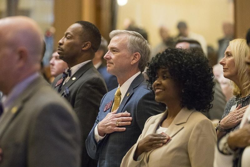 Members of the Georgia House of Representatives, including freshmen state Reps. Viola Davis and Chris Erwin, stand Monday for the singing of the national anthem during the first session in the House chambers at the state Capitol. (ALYSSA POINTER/ALYSSA.POINTER@AJC.COM)