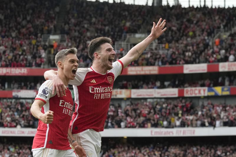 Arsenal's Leandro Trossard, left, celebrates with Arsenal's Declan Rice after scoring his side's second goal during the English Premier League soccer match between Arsenal and Bournemouth at Emirates Stadium in London, England, Saturday, May 4, 2024. (AP Photo/Frank Augstein)