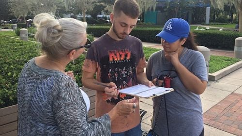Clinton campaign volunteer Gloria Lengyel helps Mike Ragusa update his voter registration while canvassing on October 4, 2016, at Lake Eola, Fla. (Steven Lemongello/Orlando Sentinel/TNS)