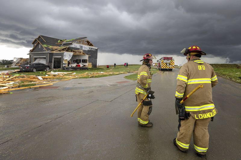 Firefighters assess the damage to houses after a tornado passed through the area near Omaha, Neb., on Friday, April 26, 2024. (Chris Machian/Omaha World-Herald via AP)