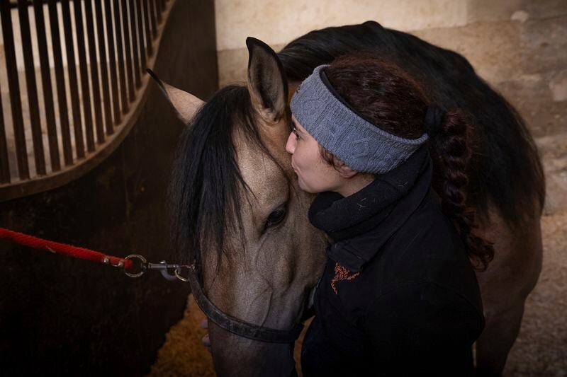 Dounia Kazzoul, 26, horsewoman at the Académie du Spectacle Equestre kisses her horse in the royal stables, in Versailles, Thursday, April 25, 2024. More than 340 years after the royal stables were built under the reign of France's Sun King, riders and horses continue to train and perform in front of the Versailles Palace. The site will soon keep on with the tradition by hosting the equestrian sports during the Paris Olympics. Commissioned by King Louis XIV, the stables have been built from 1679 to 1682 opposite to the palace's main entrance. (AP Photo/Aurelien Morissard)