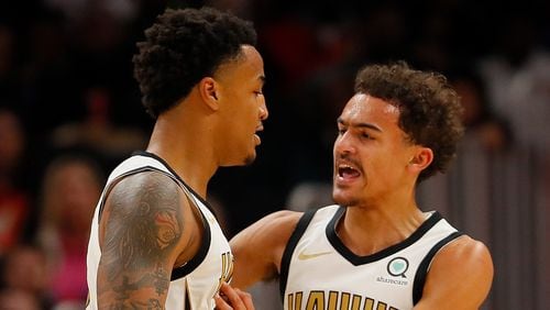 John Collins  of the Atlanta Hawks reacts with Trae Young  after dunking against the LA Clippers at State Farm Arena on November 19, 2018 in Atlanta, Georgia.
