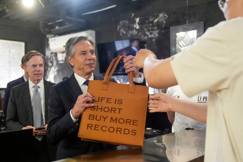 U.S. Secretary of State Antony Blinken takes a bag after buying records during a visit to Li-Pi record record store in Beijing, China, Friday, April 26, 2024. (AP Photo/Mark Schiefelbein, Pool)