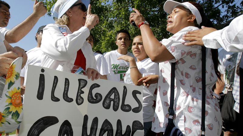 A woman holds an “ILLEGALS GO HOME” sign as she argues with another female over immigration reform during a rally in Las Vegas in May 2006. (AP Photo/Jae C. Hong)