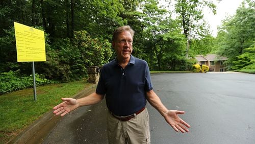 Michael Hartley stands beside the property his neighbor is trying to sell next door to his home on a cul-de-sac where a developer hopes to add around 20 new homes in Roswell. Curtis Compton/ccompton@ajc.com
