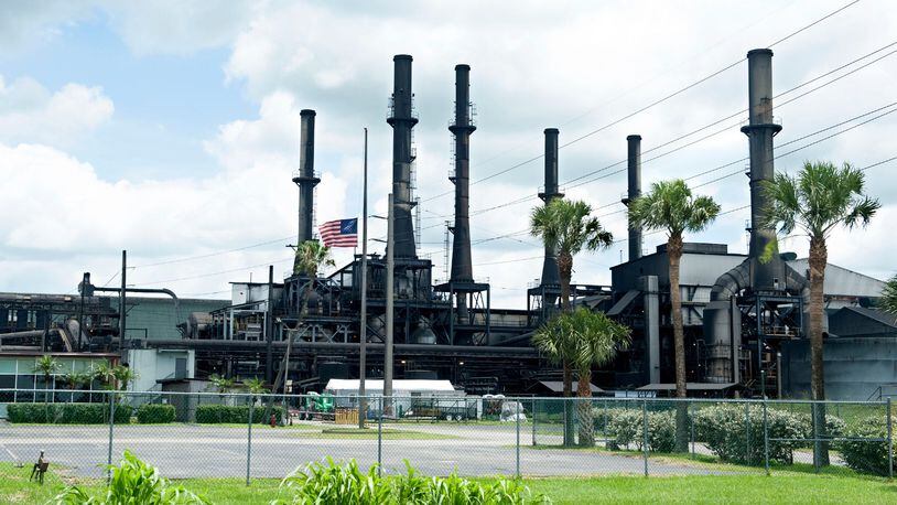 The American flag flies at half-staff at the Sugar Cane Growers Cooperative of Florida in Belle Glade on Saturday. Felix Cabrera, 86, is accused of shooting and killing a 67-year-old manager who fired him in June.