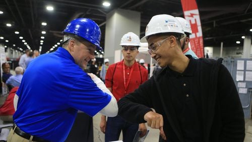 David Shea (left) and Brian Castillo (right) touch elbows during the Construction Education Foundation of Georgia (CEFGA) career expo on Thursday, March 12, 2020, at the Georgia World Congress Center. This year, additional safety measures were implemented, including mandatory hard hats and cleaning wipe-downs. (Christina Matacotta, for The Atlanta Journal-Constitution).